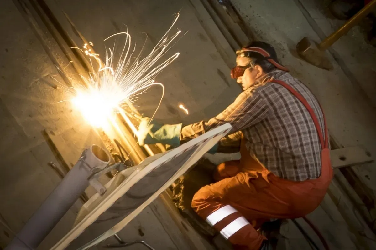 Worker welding overhead with sparks flying